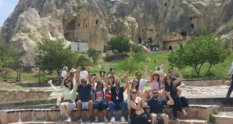 Un grupo de personas vitoreando frente a arquitectura excavada en roca.