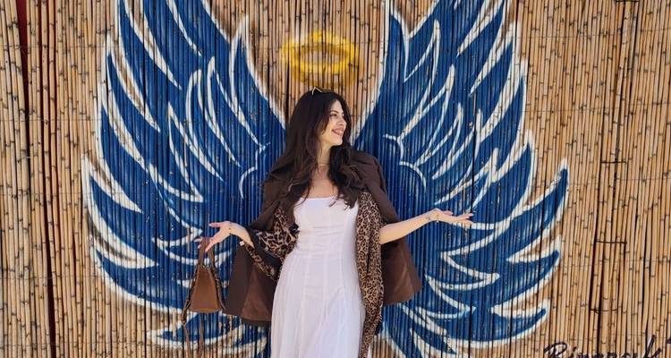 Una mujer posando contra alas de ángel pintadas en una pared.