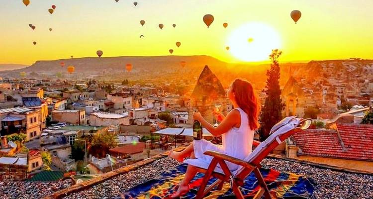 Una mujer observando globos aerostáticos al amanecer.