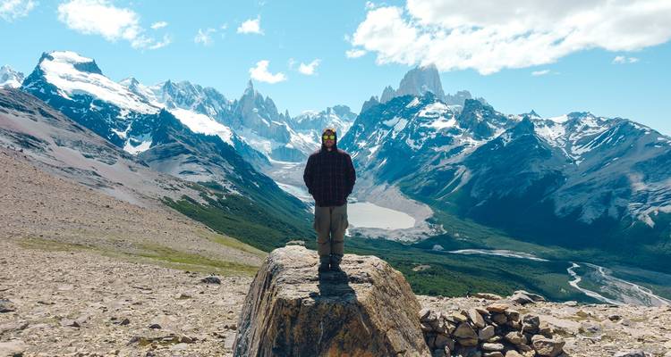 Personne debout sur un rocher avec vue panoramique sur les montagnes.