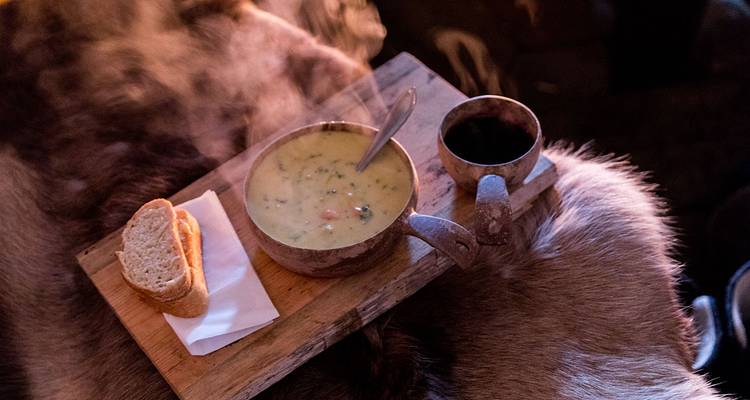 Hot soup and beverage on a wooden tray.