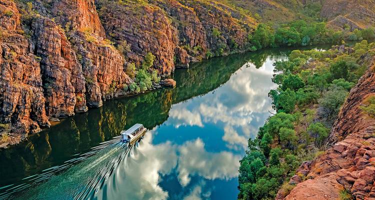 Gorge avec une rivière et un bateau, entourée de falaises et de verdure.