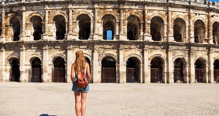 Une femme se tient debout devant un colisée de style romain.