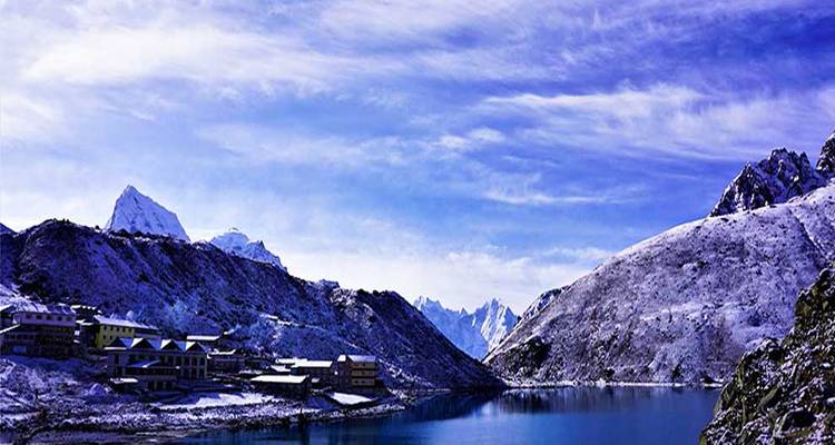 Vista panorámica de montañas nevadas y un lago sereno.