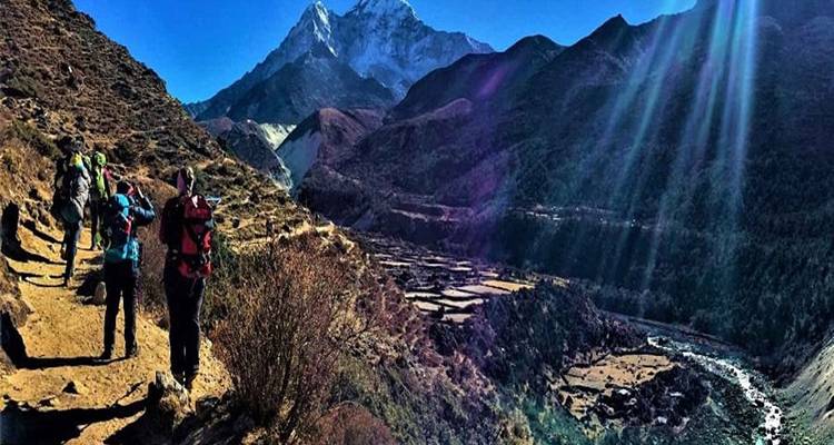 Excursionistas caminando por un sendero montañoso pintoresco con vista a un valle.