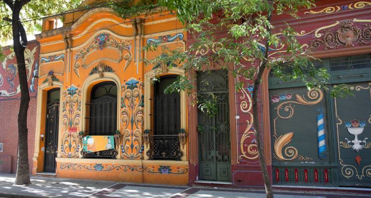 Bunte, reich verzierte Gebäudefassade an einer baumbestandenen Straße.