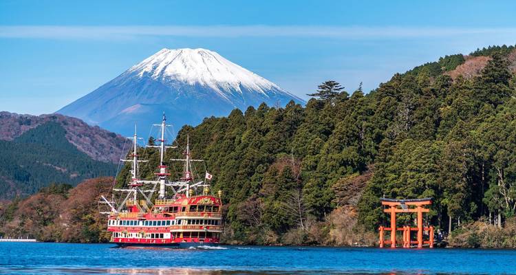 Bateau traditionnel sur un lac avec un torii et le mont Fuji en arrière-plan.