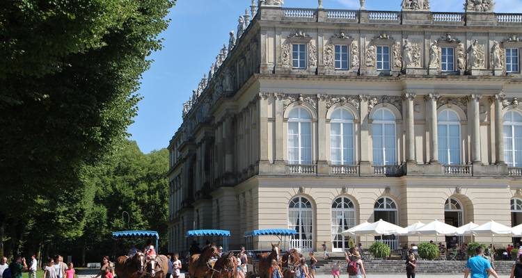 Palais orné avec des calèches à cheval devant.