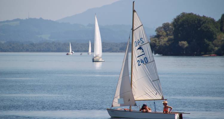 Voilier sur un lac serein avec des gens à bord.