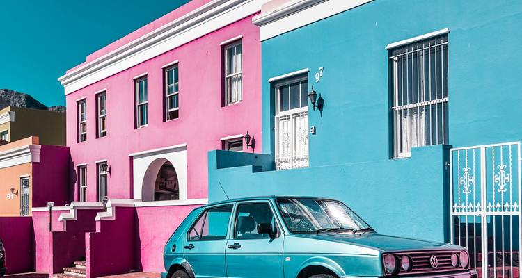 Colorful houses and a parked car in a city street.