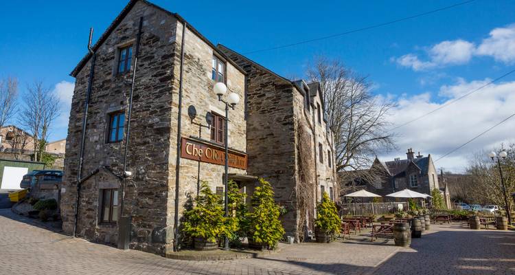 Steingebäude mit Grünpflanzen und Sitzplätzen im Freien.