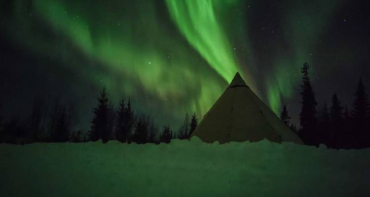 Northern lights over a snowy landscape with a traditional tent.