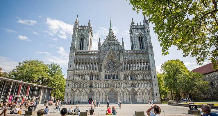 Gothic cathedral with people gathered in front, under a clear sky.