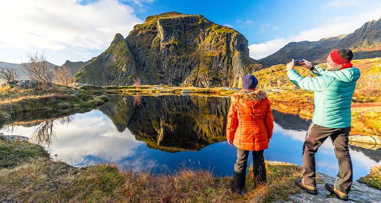 Two people admiring a reflection of a mountain on a lake.