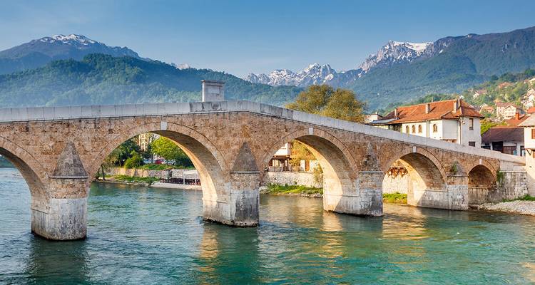 Pont au-dessus d'une rivière avec des montagnes à l'arrière-plan.