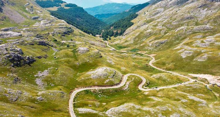 Personne assise sur la berge d'une rivière avec vue sur des bâtiments historiques.