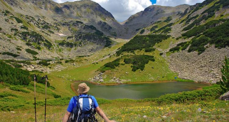 Hiker sitting and admiring a mountainous landscape with a lake.