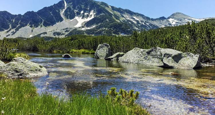 Mountain landscape with clear water and boulders.