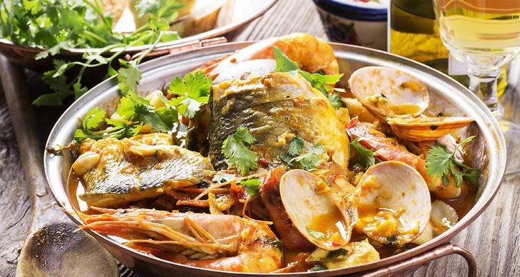 Plat de fruits de mer avec poisson, crevettes et herbes dans un bol traditionnel.