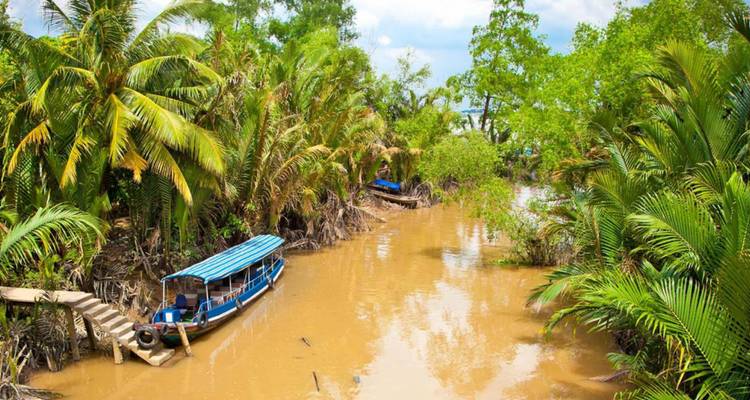 Scène de rivière tropicale avec des bateaux et des palmiers verts luxuriants.