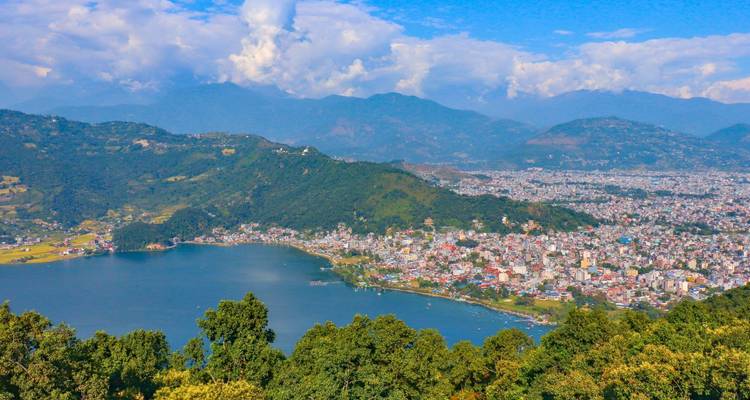 Vista aérea de una ciudad junto a un lago con montañas al fondo.