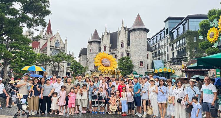 Grupo turístico muy grande frente a castillos de estilo de cuento de hadas y exhibición de girasoles gigantes en un pueblo de parque temático