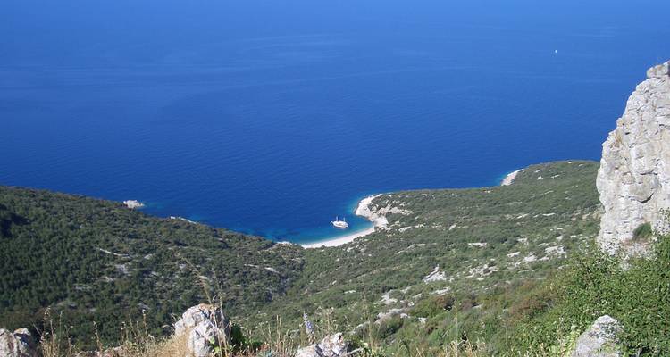Abgeschiedene Strandbucht, betrachtet von einem Hügel mit Blick auf das tiefblaue Meer.