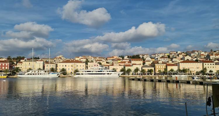 Hafen mit Booten und Ufergebäuden unter einem teilweise bewölkten Himmel.