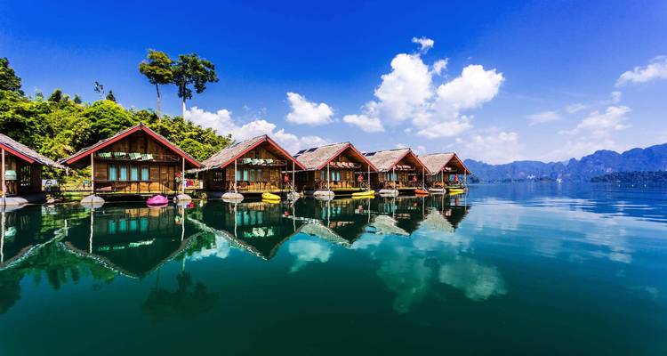 Floating bungalows on a calm lake with a mountain backdrop.