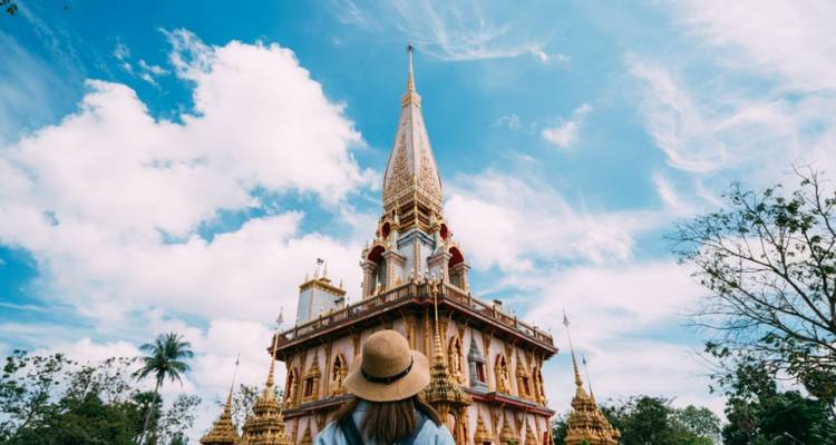 Femme regardant vers le haut vers un temple sous un ciel partiellement nuageux.