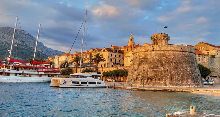 Fuerte histórico y barcos en un puerto bajo un cielo azul.