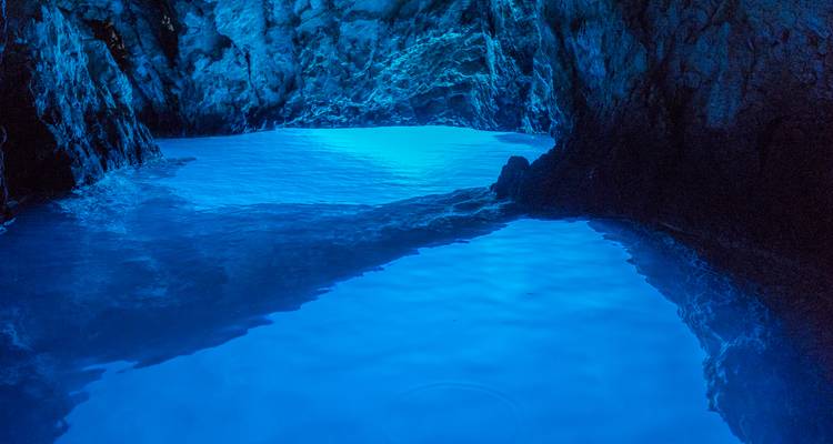 Dentro de una cueva con iluminación azul y agua cristalina.