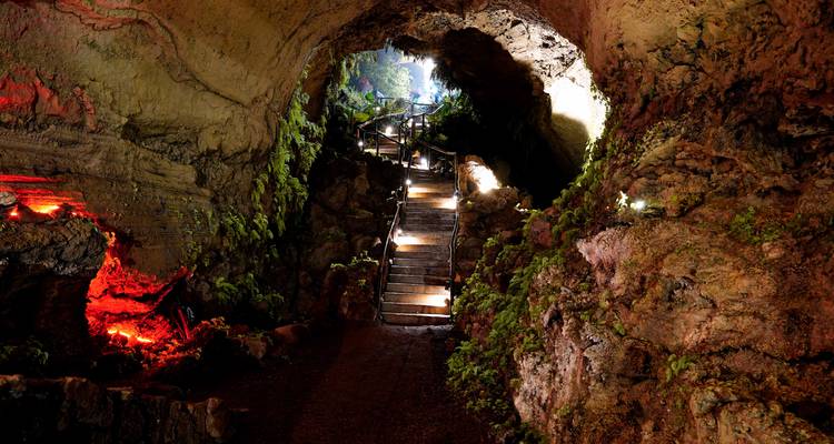 Illuminated cave with stairs leading inside.