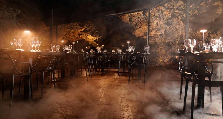Elegantly set restaurant table in a dimly lit cave.