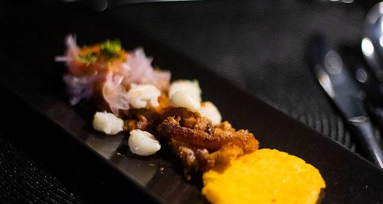 Gourmet dish beautifully presented on a black plate.