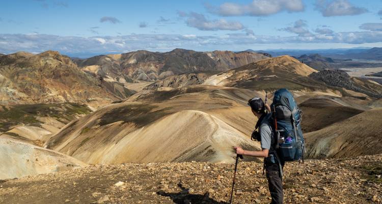 Hiker with a backpack looking over rugged Icelandic terrain.