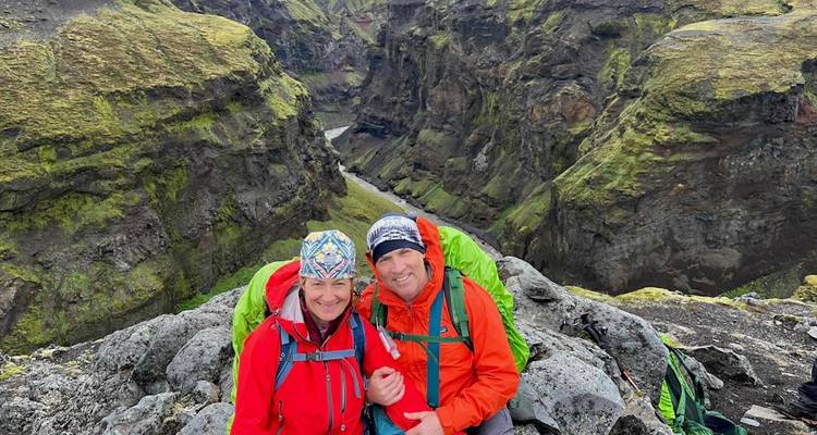Couple in hiking gear posing with a rocky gorge in the background.