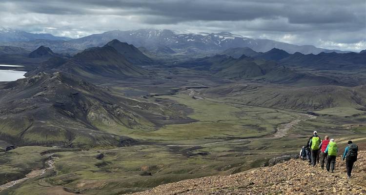 Hikers on a mountain trail with vast landscape view.