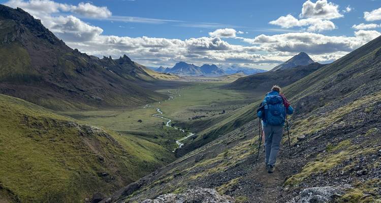 Randonneur marchant le long d'une vallée verdoyante.