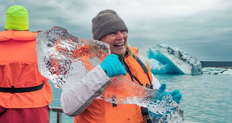 Tourist holding ice by glacier lagoon.