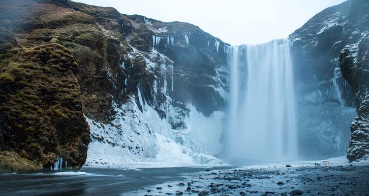 Skogafoss waterfall with partially frozen surroundings.