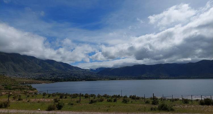 Groot meer omringd door bergen onder een gedeeltelijk bewolkte hemel.