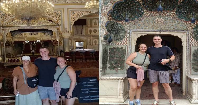 Three people posing inside an ornate building with decorated walls, and an entrance with peacock motifs.