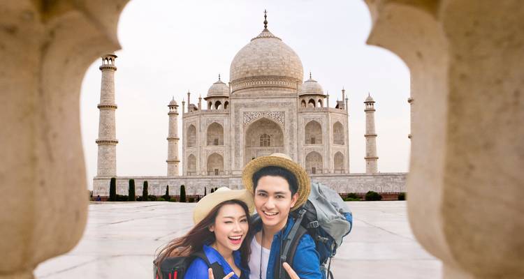 Couple posing in front of the Taj Mahal with smiles.