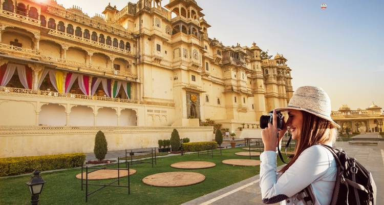 Tourist, der ein Foto vom Stadtpalast von Udaipur bei lebhaftem Sonnenuntergang macht.