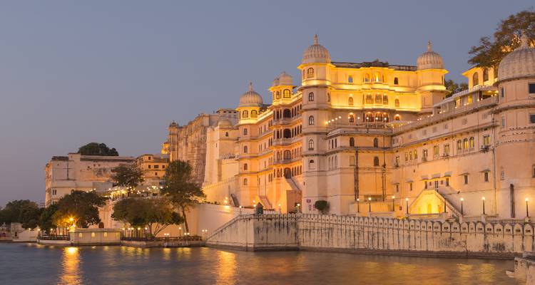 Vista nocturna de las luces del Palacio de la Ciudad de Udaipur reflejándose en el agua.