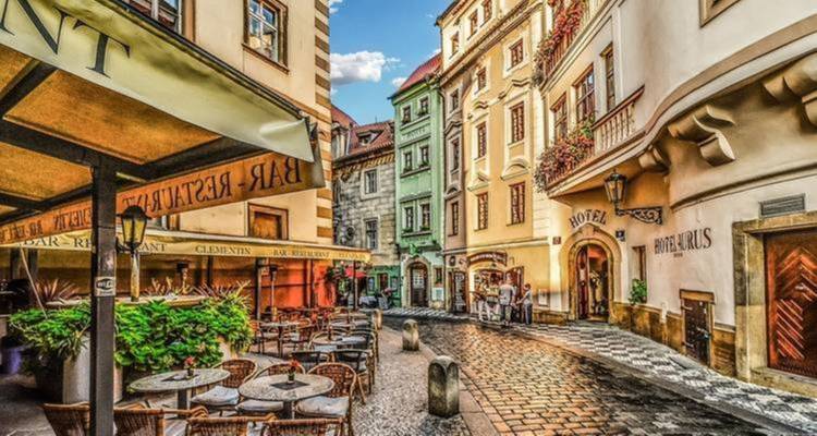 Calle histórica colorida en Praga con cafés al aire libre.