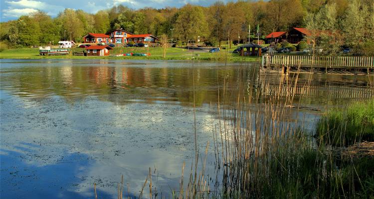 Meer-resort gebied met houten gebouwen en steigers omgeven door groen.