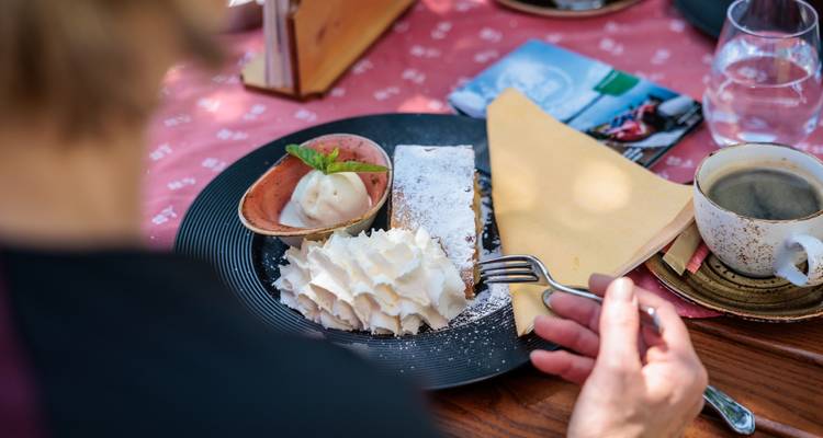 Person enjoying a dessert with whipped cream and coffee.