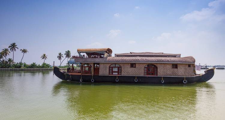Traditional houseboat on calm waters with a clear sky.